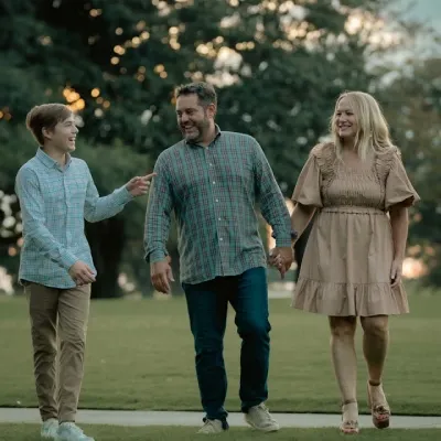 Billede af glad og tryg familie, der går i en park.